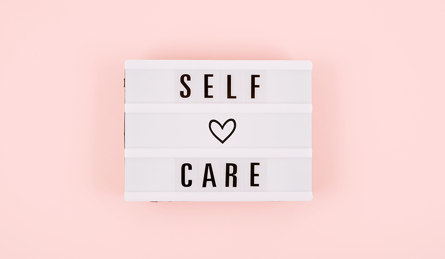 self-care-word-lightbox-flower-narcissus-pink-background-flat-lay